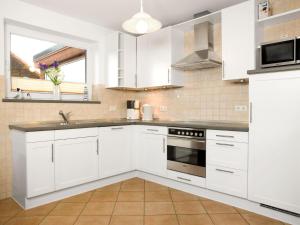 a white kitchen with white cabinets and a sink at Haus Meernixe in Kaltenhof