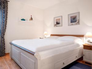 ein weißes Bett in einem Schlafzimmer mit zwei Bildern an der Wand in der Unterkunft Gollwitzer Park Oase in Insel Poel