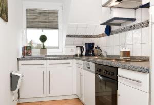 cocina con armarios blancos, fregadero y ventana en Gollwitzer Park Seesternchen, en Poel