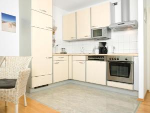 cocina con armarios blancos, mesa y silla en Appartements Am Reiterhof Am Reitstall, en Poel