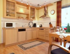 a kitchen with wooden cabinets and a microwave and a table at Ferienwohnungen Fischerstieg Hafenblick in Timmendorf