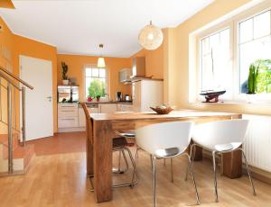 eine Küche mit einem Holztisch und weißen Stühlen in der Unterkunft Doppelhäuser Timmendorf Strand Haus Taun Lüchttorm in Insel Poel