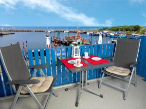 a table and chairs on a balcony with a marina at Kleine Hafenkoje in Insel Poel