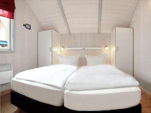 een groot wit bed met 2 kussens in een kamer bij Dänisches Ferienhaus in Kaltenhof