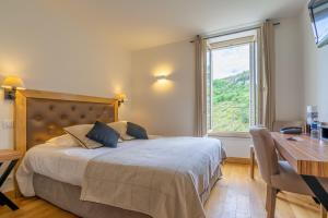 a bedroom with a bed, desk, chair and window at Hotel Beau Site - Rocamadour in Rocamadour