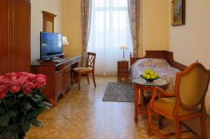 um quarto de hotel com um quarto com uma cama e uma televisão em Bristol Kralovska Vila em Karlovy Vary