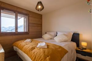 a bedroom with a bed with towels on it at ODYSSEE B102 Cosy appartement sur les pistes in La Toussuire