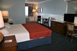 a hotel room with a bed and a desk and a television at Avenue Inn & Spa in Rehoboth Beach