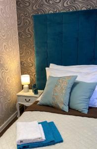 a bed with a blue headboard and a blue towel on it at Penzión Aira in Zvolen