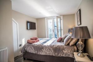 ein Schlafzimmer mit einem Bett mit einer Lampe und einem Fenster in der Unterkunft Courtyard Holiday Homes in Southport