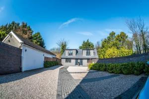 ein Haus mit einem Steinzaun und einer Auffahrt in der Unterkunft Courtyard Holiday Homes in Southport