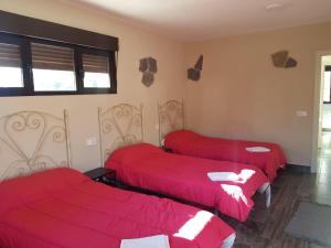 three beds in a room with red sheets at Paraiso del Alberche in Navaluenga
