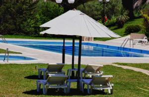 a group of chairs and an umbrella next to a pool at Rebecca's Village Corfu Hotel in Karousádes