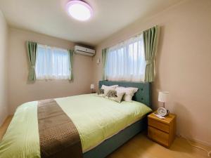 a bedroom with a bed with a green headboard and windows at 福恵館 in Fukuoka