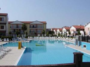 una grande piscina blu con sedie e edifici di Villaggio Adriatico villetta a schiera 01 a Rosolina Mare