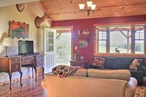 a living room with a couch and a desk with a television at Rural Farmhouse Cabin on 150 Private Wooded Acres! in Mayville