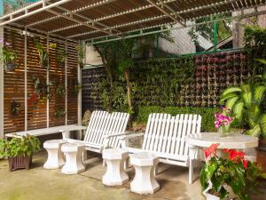 3 chaises blanches et une table sur une terrasse dans l'établissement Patumwan House, à Bangkok