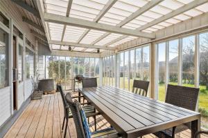 a screened porch with a wooden table and chairs at Tklhus Aeroe in Ærøskøbing