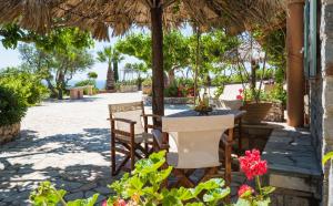 a patio with a table and chairs under an umbrella at Palaeopoli Villas in Avlemonas