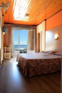 a bedroom with a large bed and a large window at Hotel Grecs in Roses