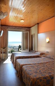 a hotel room with two beds and a large window at Hotel Grecs in Roses
