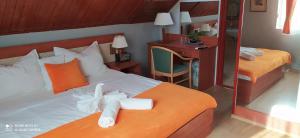 sypialnia z 2 łóżkami z pomarańczowymi poduszkami i biurkiem w obiekcie Hermina Panzió w Siófoku