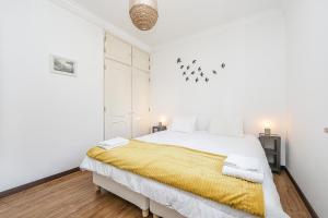 um quarto branco com uma cama grande e um cobertor amarelo em Spacious Beach and Golf Villa em Charneca