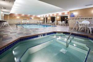 uma piscina num quarto de hotel com mesas e cadeiras em Holiday Inn Express Hotel & Suites Fort Collins, an IHG Hotel em Fort Collins