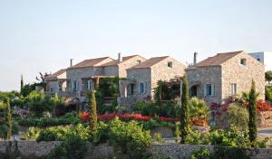 a row of stone houses with flowers in a garden at Palaeopoli Villas in Avlemonas