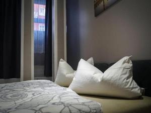 a bed with white pillows in a bedroom with a window at Amaya Motel in Berlin