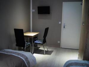a room with a table and two chairs and a television at Amaya Motel in Berlin