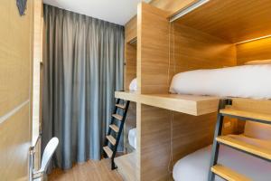 a small bedroom with a bed and a bunk bed and a ladder at Atnest Hostel in Bangkok