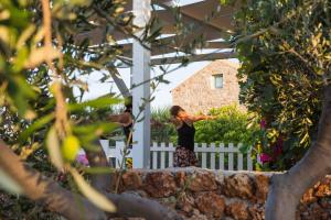 a woman standing in front of a white fence at Palaeopoli Villas in Avlemonas