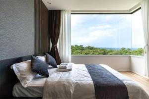 um quarto com uma cama e uma janela grande em Ocean Villa Fuchaku Okinawa / Vacation STAY 79452 em Onna