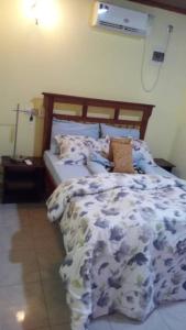 a bedroom with a bed with a blue and white comforter at Rose Garden Apartments in Limbe