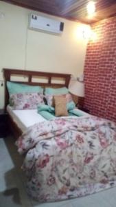 a bedroom with a bed and a brick wall at Rose Garden Apartments in Limbe