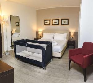 ein Schlafzimmer mit einem Bett und einem roten Stuhl in der Unterkunft Best Western Plus Hotel Modena Resort in Formigine