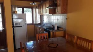a kitchen with a table and a white refrigerator at Lago Puelo Departamentos Turisticos in Lago Puelo