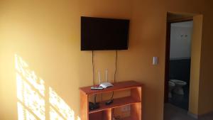 a room with a television on a wall with a table at Lago Puelo Departamentos Turisticos in Lago Puelo