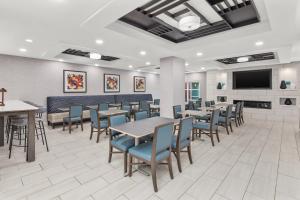 a dining room with tables and chairs and a flat screen tv at Holiday Inn Express Hotel & Suites Greenville-I-85 & Woodruff Road, an IHG Hotel in Greenville