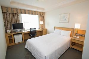 een hotelkamer met een bed, een bureau en een televisie bij Keio Plaza Hotel Hachioji in Hachioji