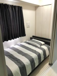um quarto com uma cama listrada a preto e branco em Cocostay KO Residence Sennichimae#603ココステイ ケーオーレジデンス センニチマエ#603 em Okayama