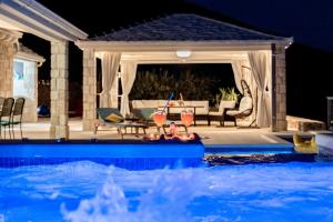 a swimming pool at night with two glasses of wine at Villa Blue Sky in Bol +32 photos
