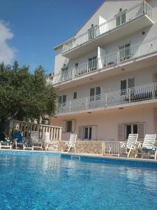 um hotel com piscina em frente a um edifício em Apartments Antonio em Cavtat