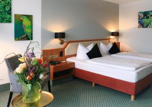 a hotel room with a bed and a vase of flowers at AVIA Hotel in Regensburg