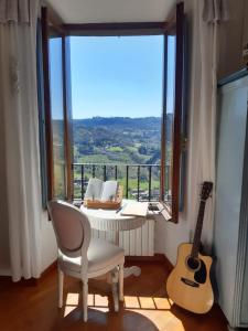 ein Zimmer mit einem Stuhl und einer Gitarre vor einem Fenster in der Unterkunft Ripa Medici, camere con vista e parcheggio incluso in Orvieto