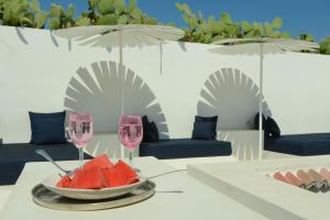 a table with a bowl of watermelon and two glasses of wine at Dar Sabri in Nabeul
