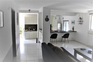 a living room and kitchen with a couch and chairs at Rez de villa avec beau jardin et belle vue in Saint-Laurent-du-Var