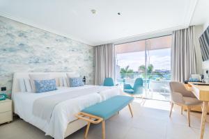 a bedroom with a large bed and a desk and chairs at Hotel Lava Beach in Puerto del Carmen