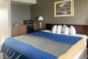a hotel room with a bed with blue sheets and pillows at Lakeview Inn in Lake Saint Louis